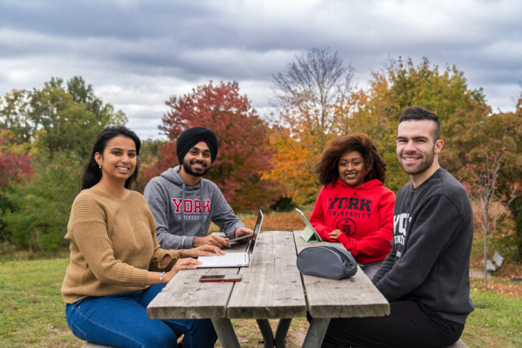 Students sitting at a picnic table with electronics