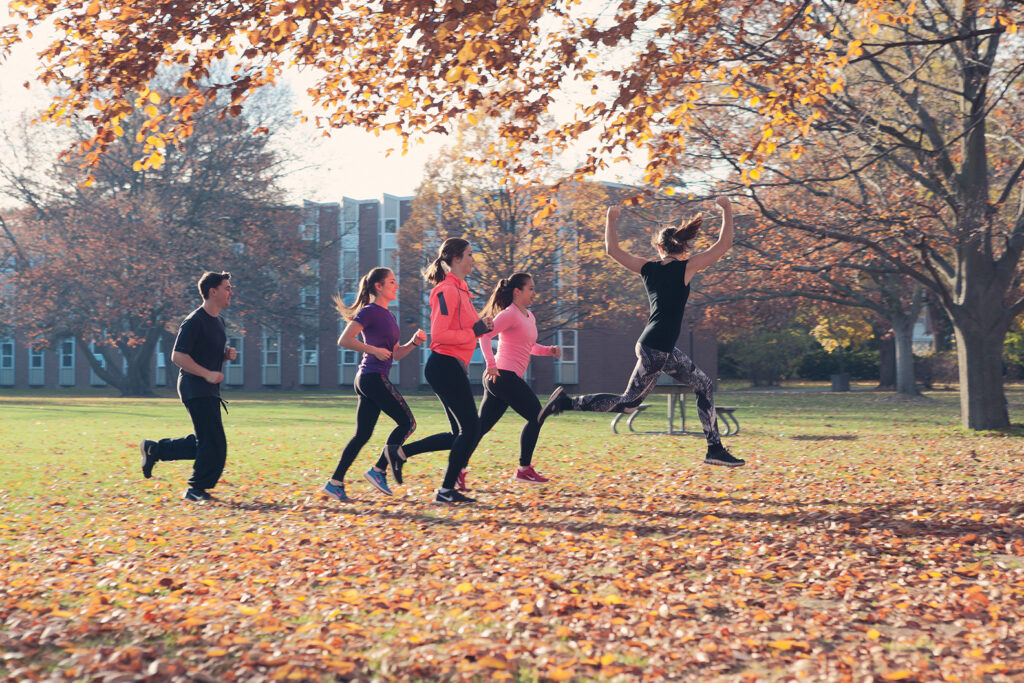 Group of 5 people running on grass