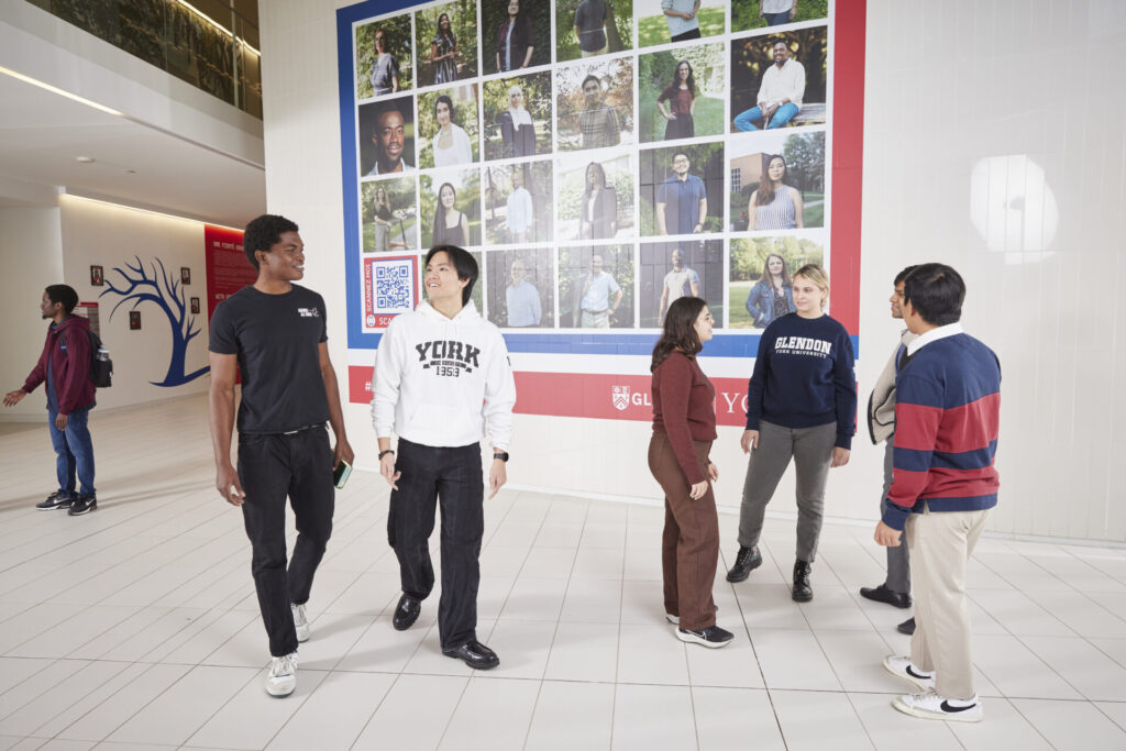 Students walking and talking in front of a wall mural.