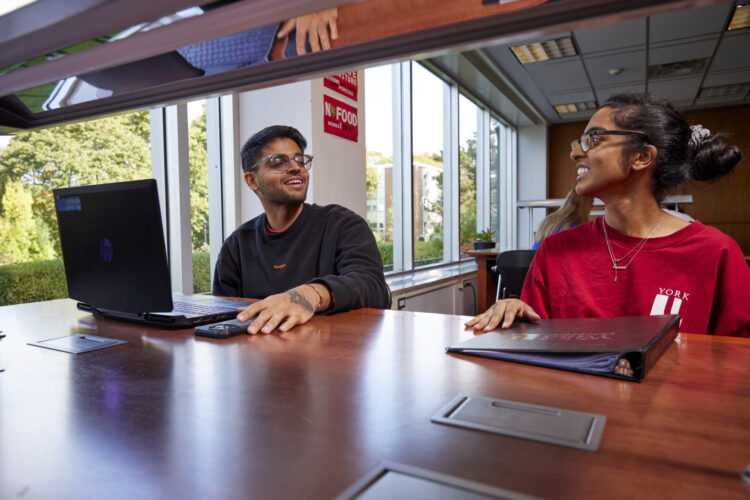 Two students studying together with laptop and notebook