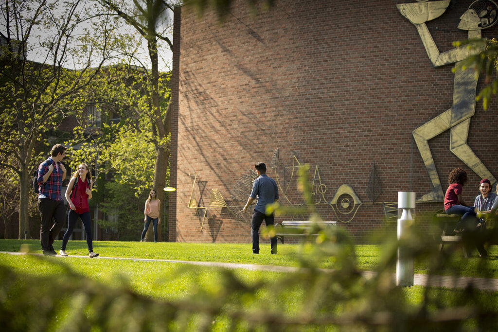 Students walking and playing frisbee on school campus