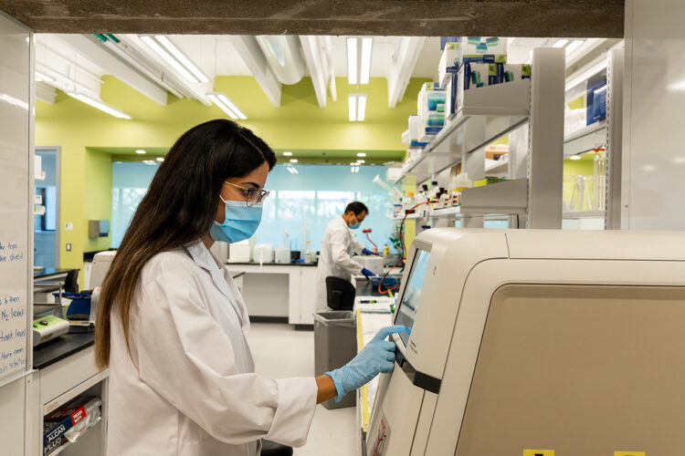 Man and woman wearing lab coats and masks in a lab