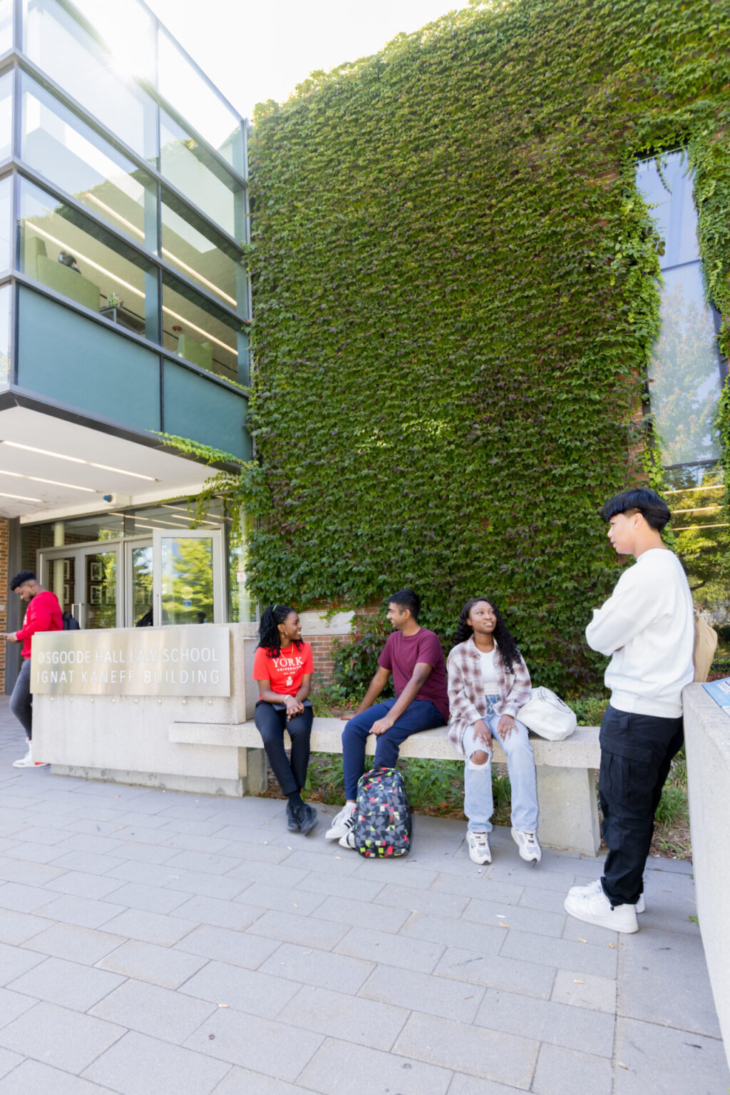 Students sitting outside a building with a plant wall