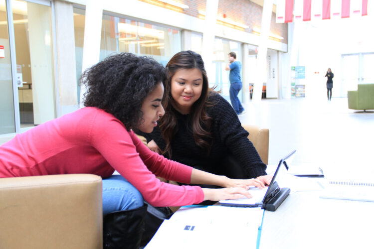 Two women sitting in the lobby and looking at a laptop