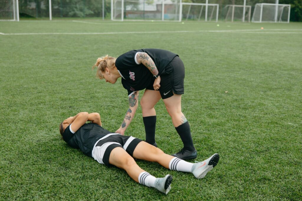 Woman in black shirt and black shorts lying on green grass field