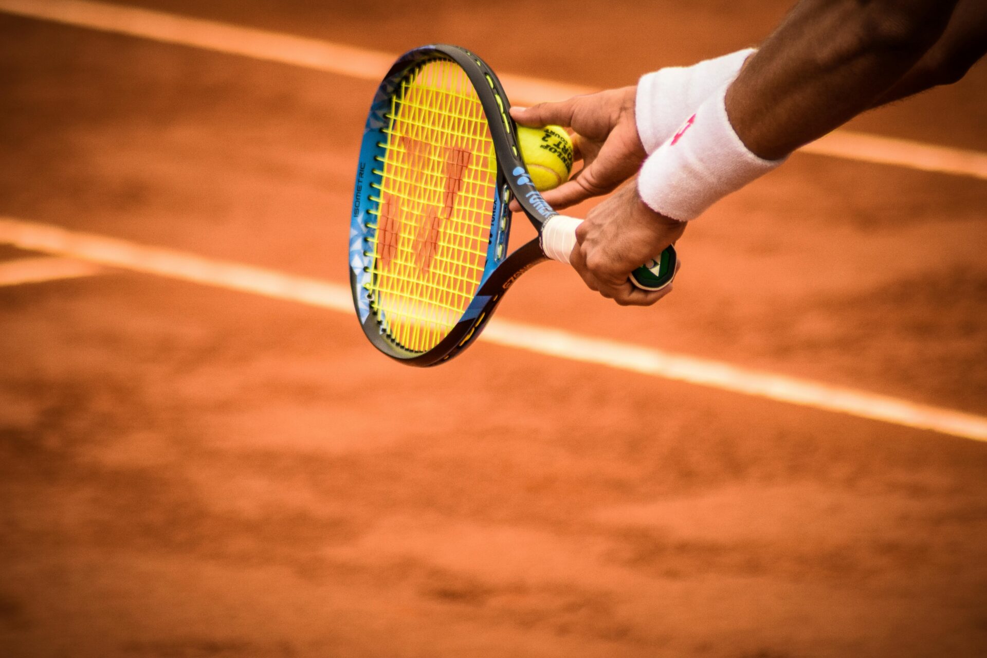 Person holding tennis ball and racket