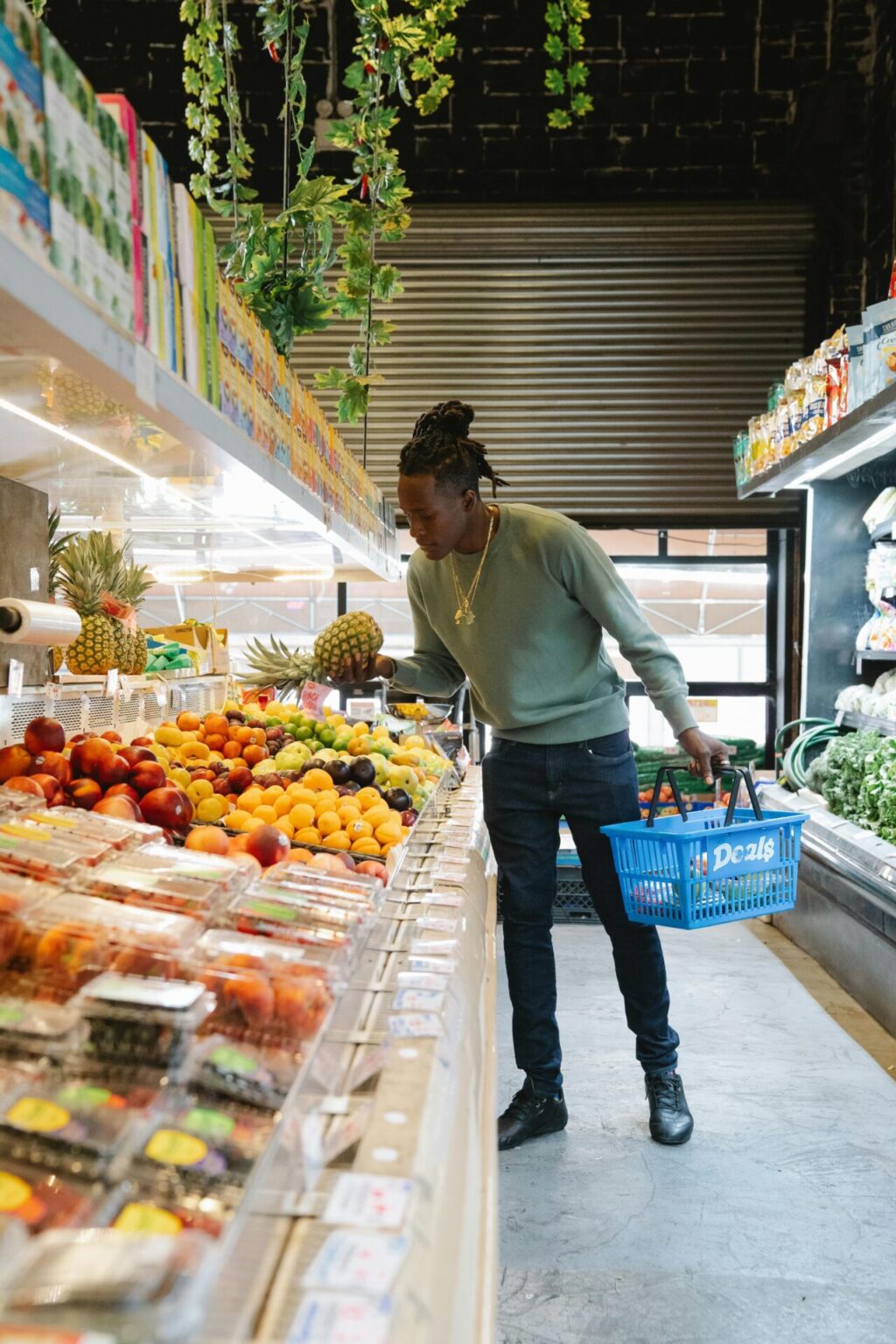 man in grocery store picking pineapple