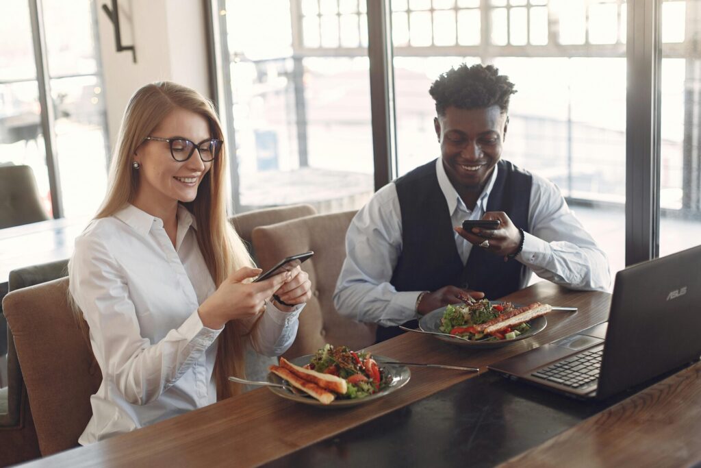 Two people using phones during lunch in cafe