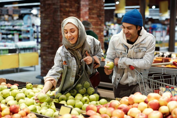 Two people picking out apples at grocery store