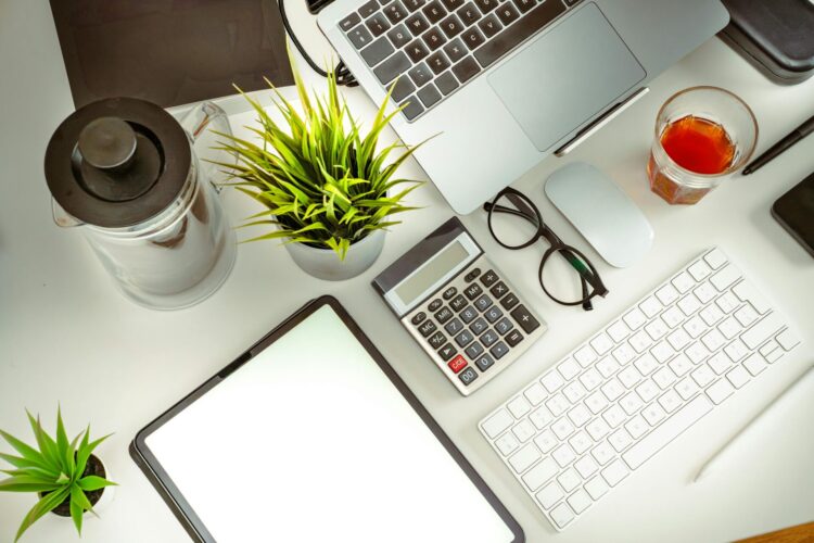 Office desk with plants, keyboard, computer and calculator