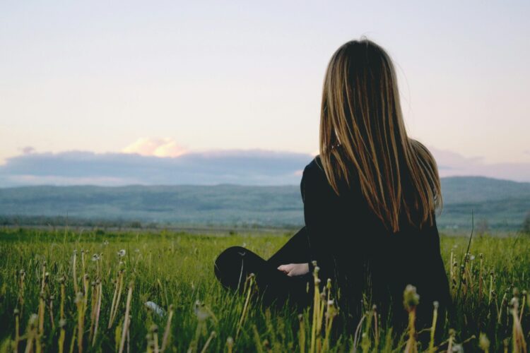 Woman sitting on green grass field