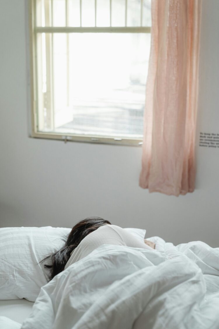 Person sleeping in the bed next to window