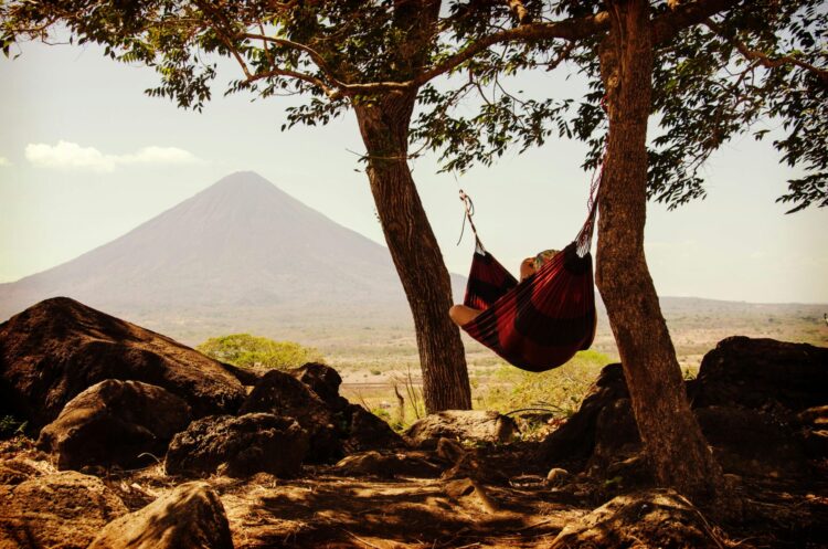 Person lying on a hammock beside mountain