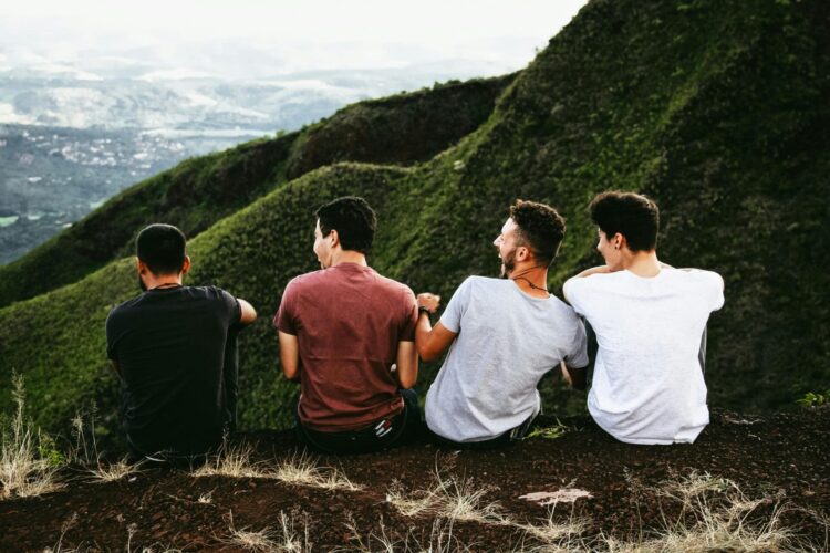 men sitting on ground overlooking mountains