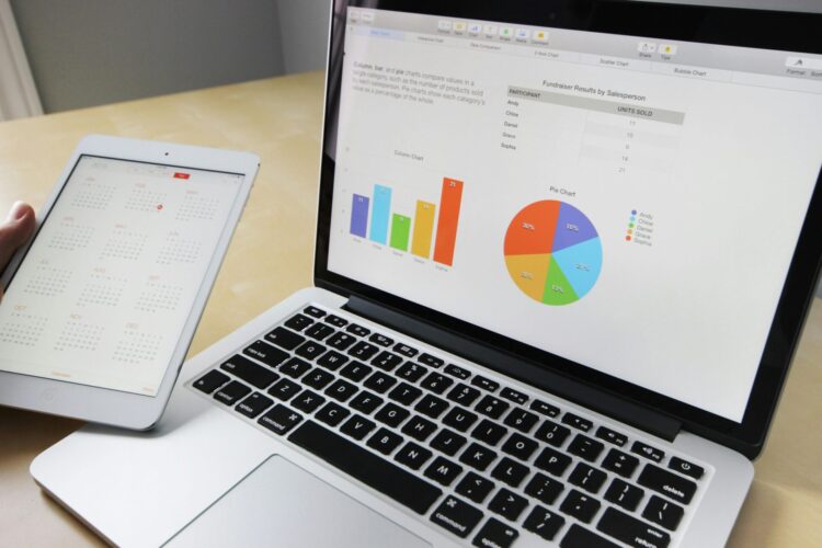 Tablet with calendar and laptop screen with graphs and charts