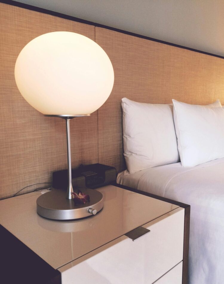 Silver and white desk lamp beside bed