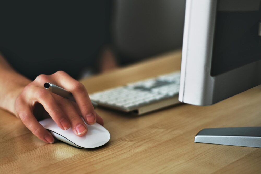 Person holding mouse in front of computer