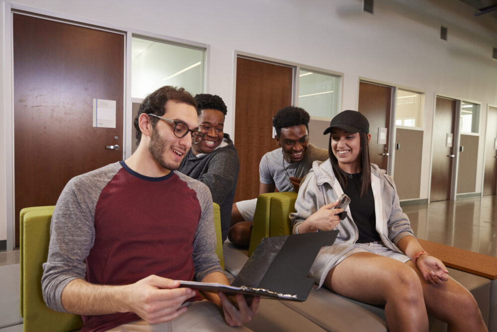 Students sitting in the lobby looking at a folder