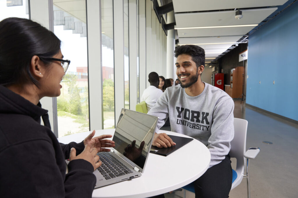 Two students sitting at the table with a laptop