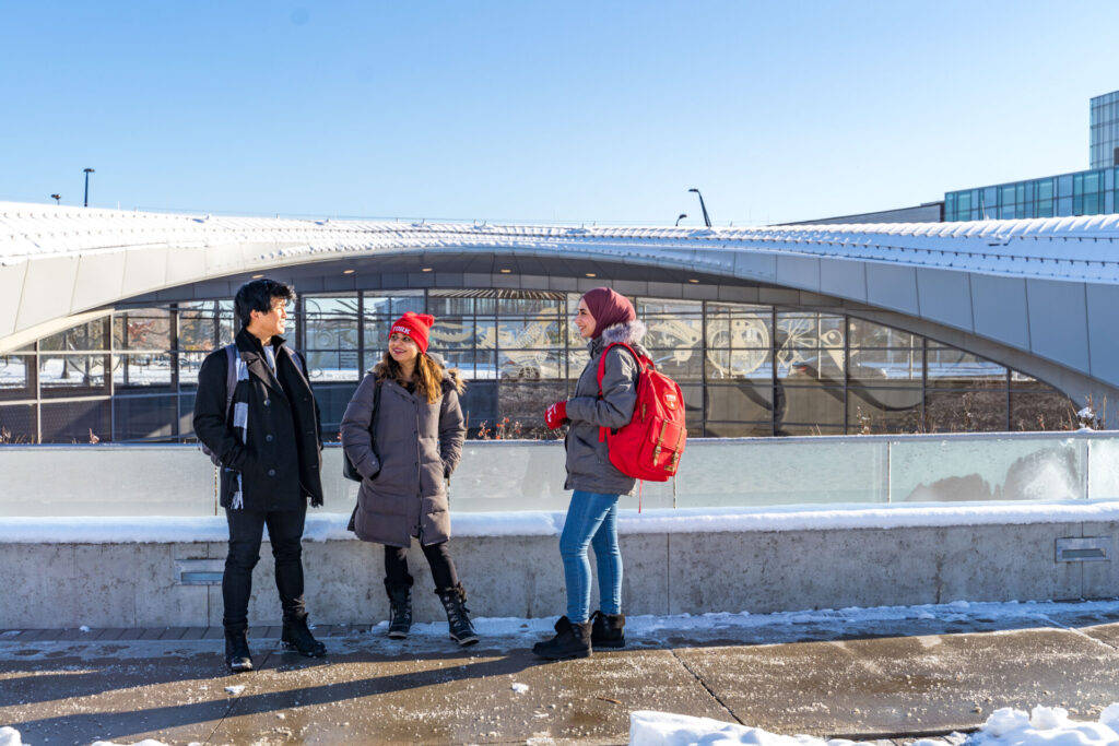 Three friends standing in front of a subway station and talking