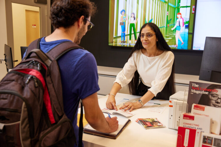 Staff helping student at the front desk