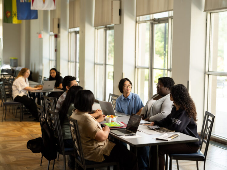 Group of students sitting around the table with laptop and notebooks