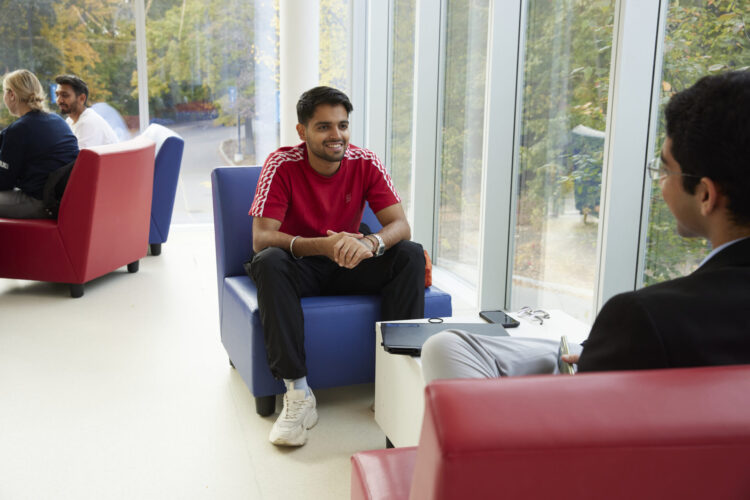 Students sitting down on a sofa chair talking