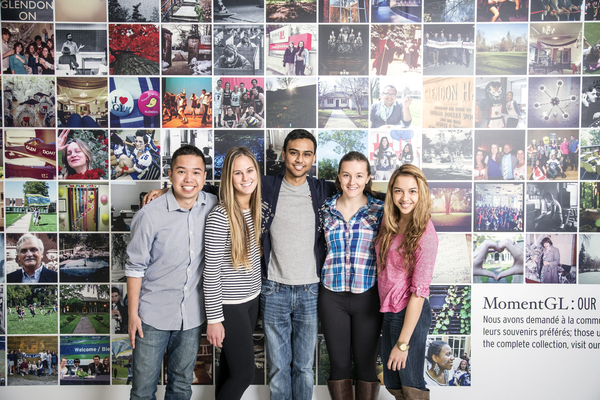 Students standing and hugging in front of a mural