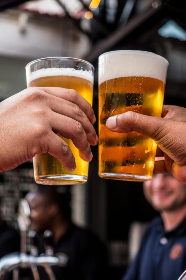 Two people holding drinking glasses filled with beer