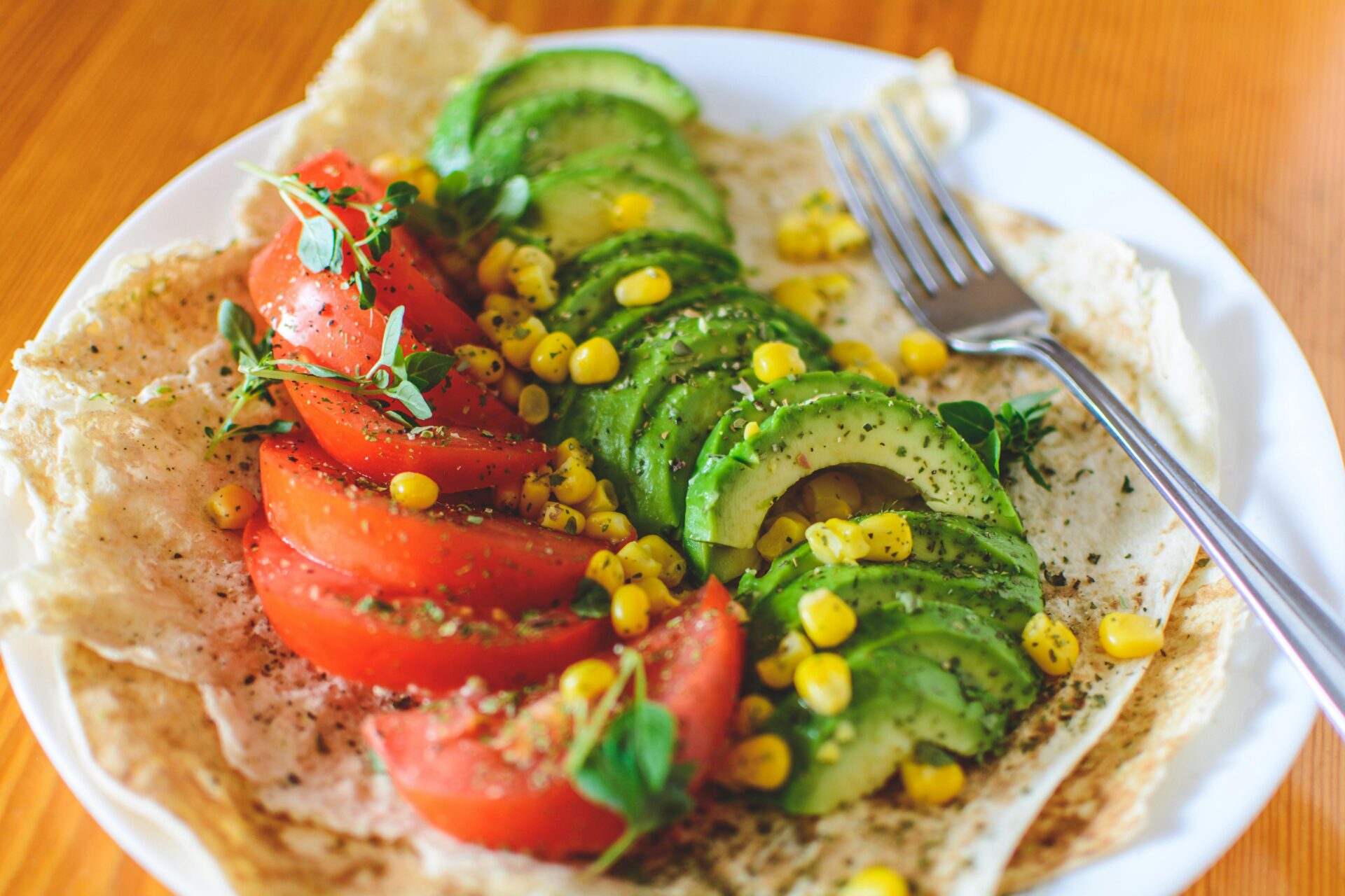 Sliced tomato and avocado on white plate