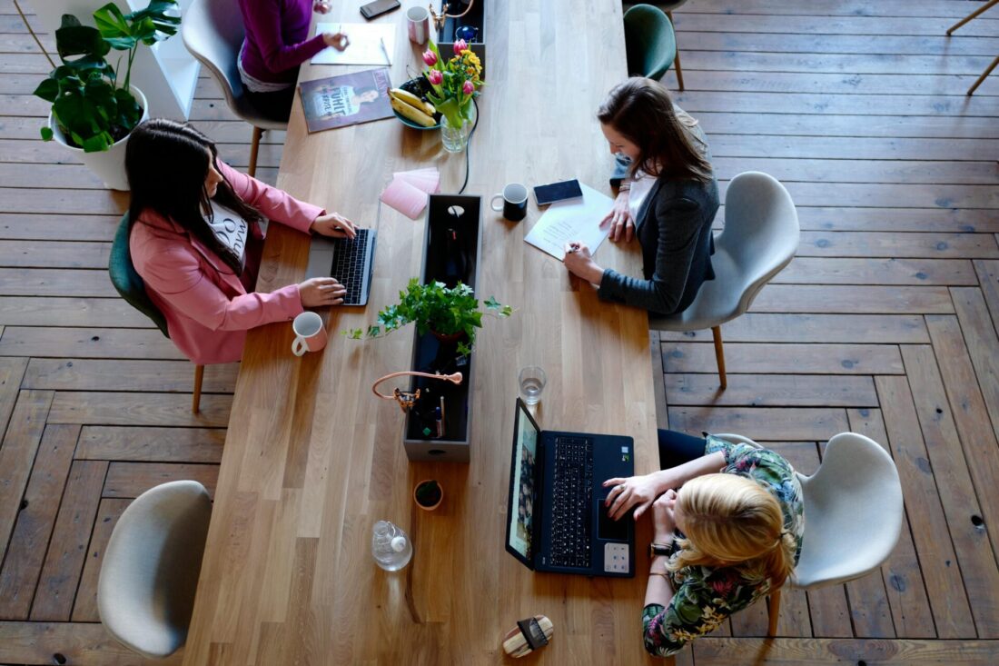 Three people sitting on white chairs in front of table