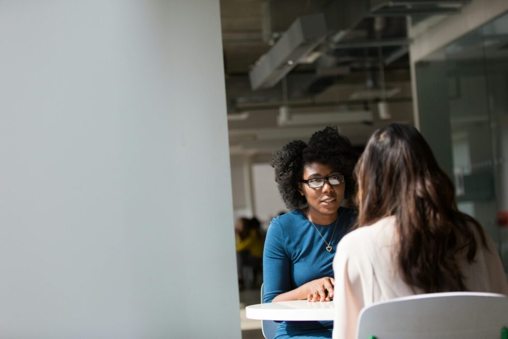 Women wearing blue talking to another women at a table