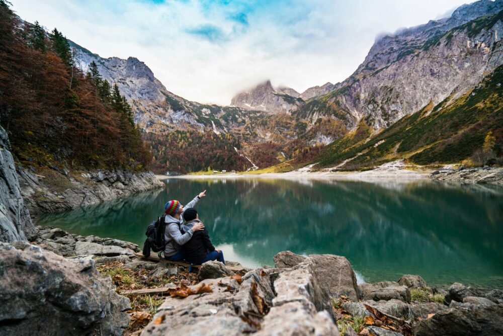 Couple sitting on rock beside lake