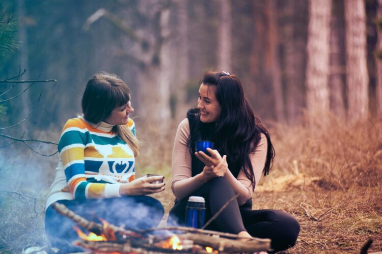 Two women sitting on the ground near bonfire