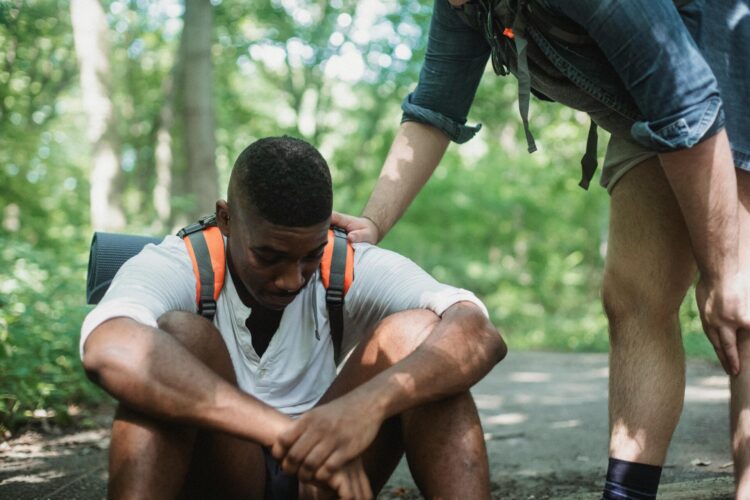 Unhappy hiker sitting on the floor being consoled