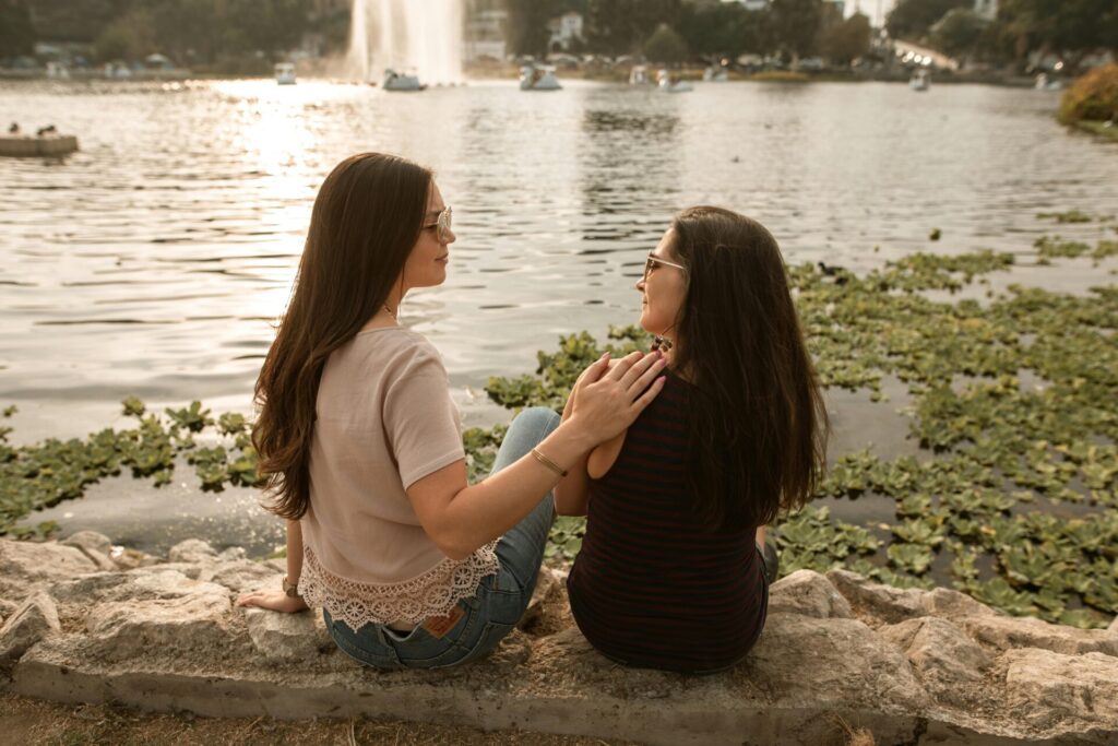 Two women sitting by a lake