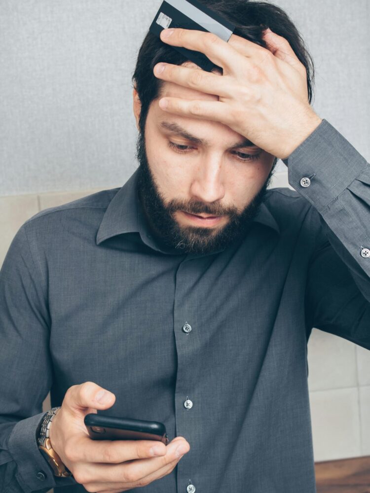 man in shirt holding his hand over his forehead