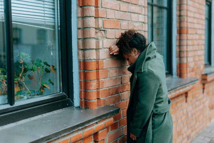 Women in a green coat leaning on the wall