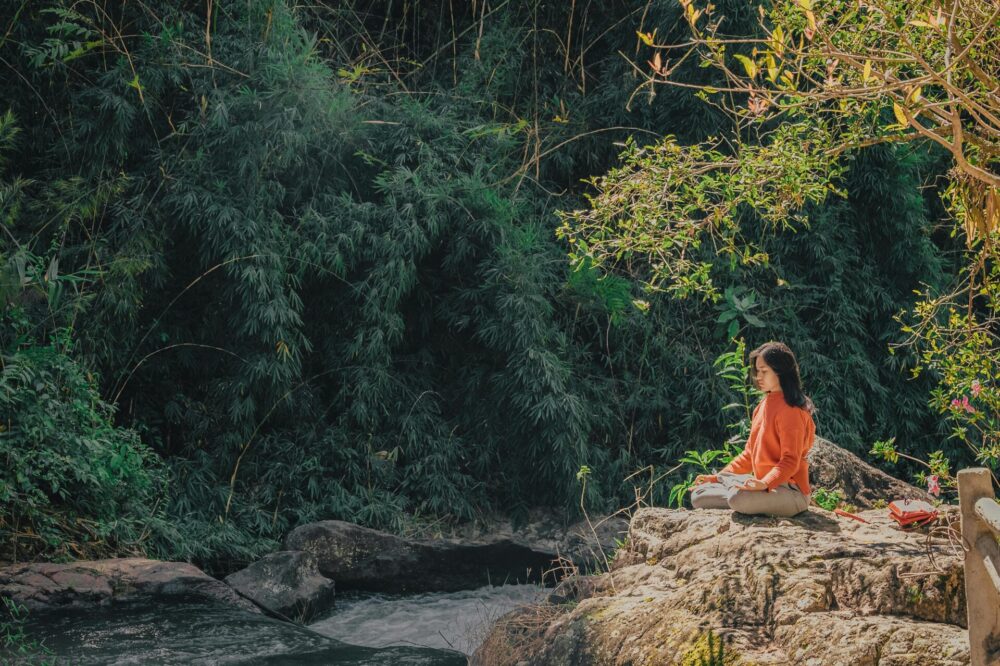 Woman sitting on stone near trees