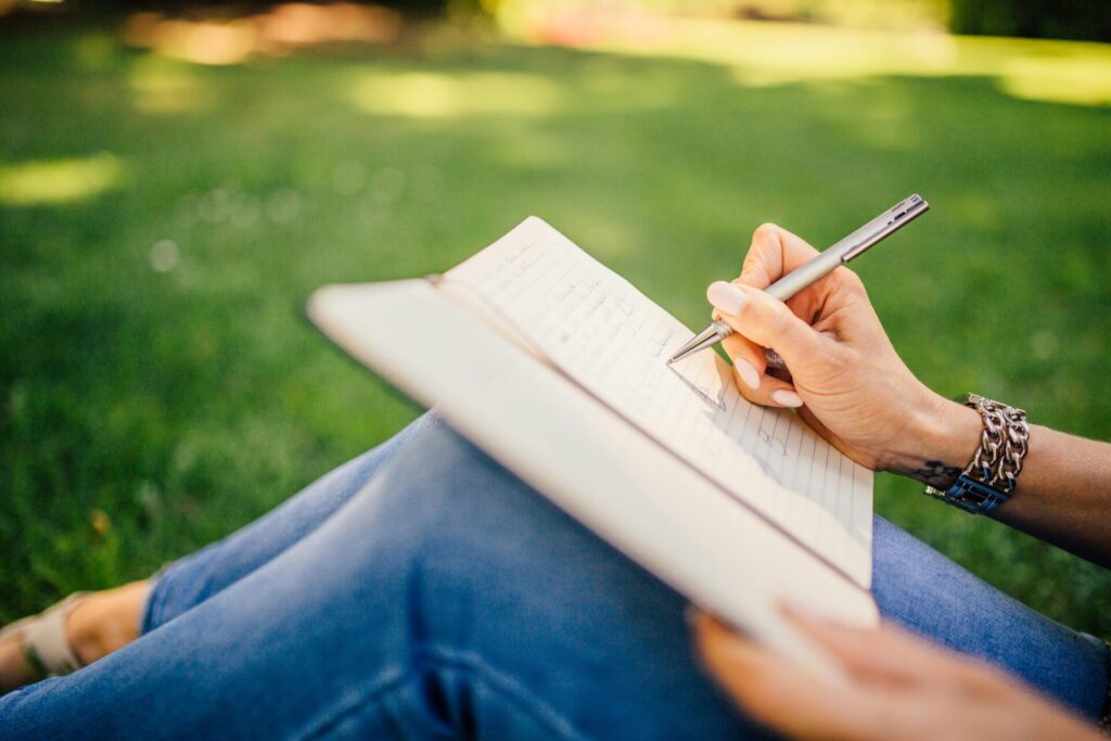 Person writing in notebook with pen