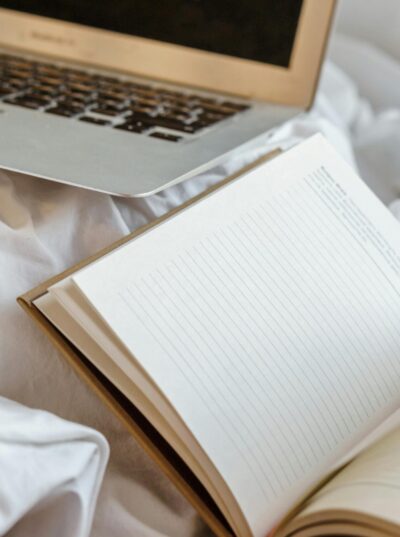 Open diary near laptop on crumpled bed