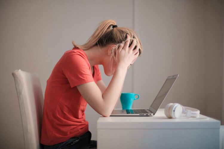 Woman resting head of hands and looking at her laptop