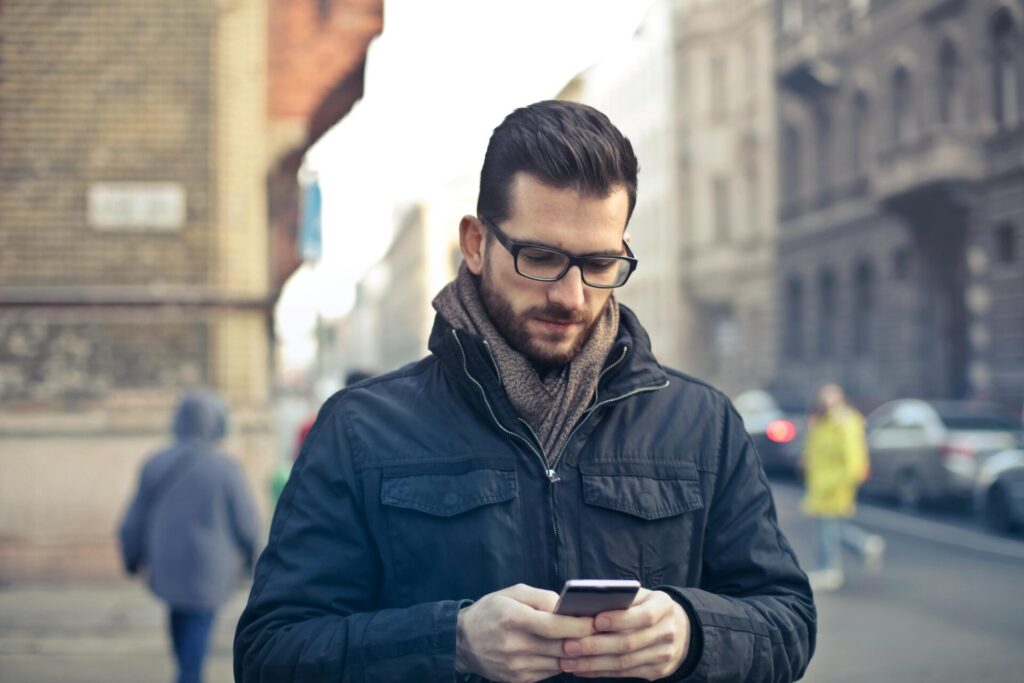 Person holding his phone in a jacket outside