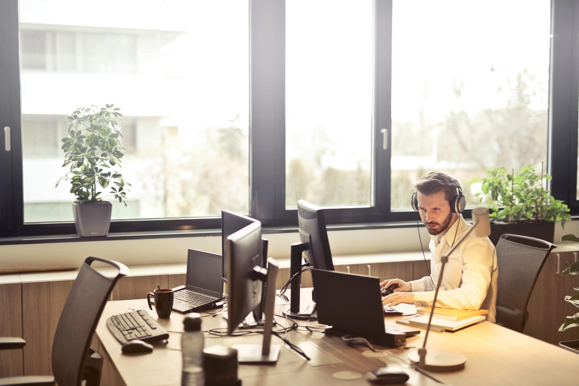 Man with headphones facing computer in office