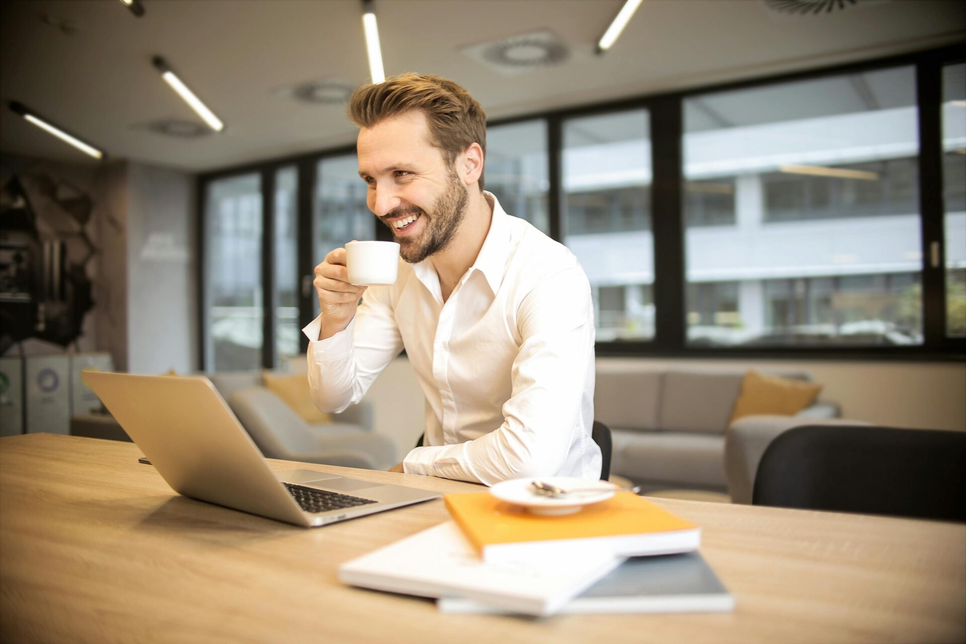 Man sitting on chair while holding cup in front of table