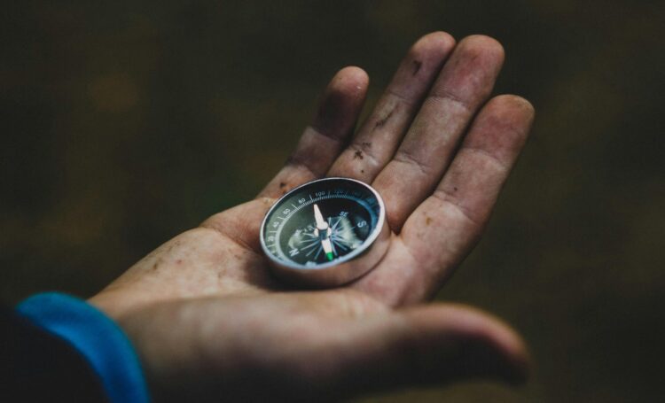 Person holding gray and black compass in hand