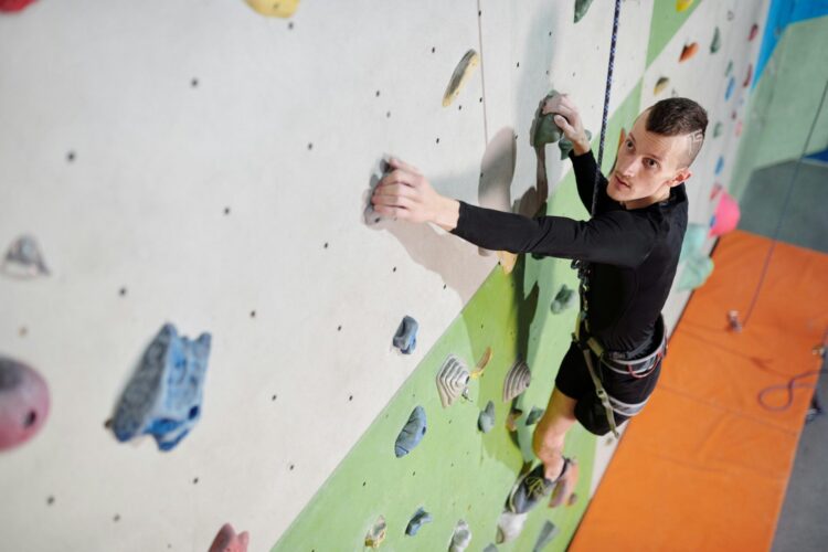 Man in black long sleeve shirt and black pants climbing on wall