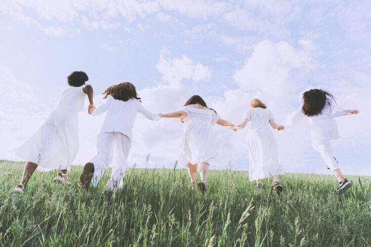 People holding hands walking up a grass hill