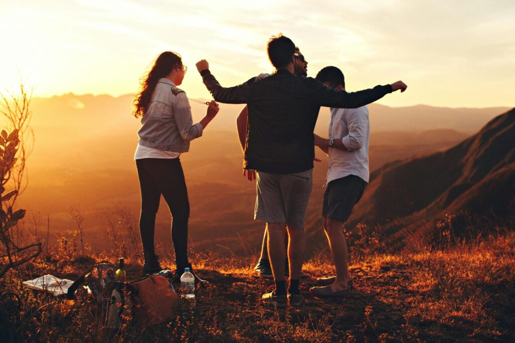 Four people standing at top of grassy mountain