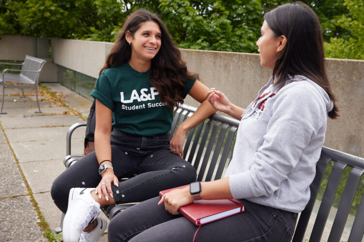 Two people talking on a bench